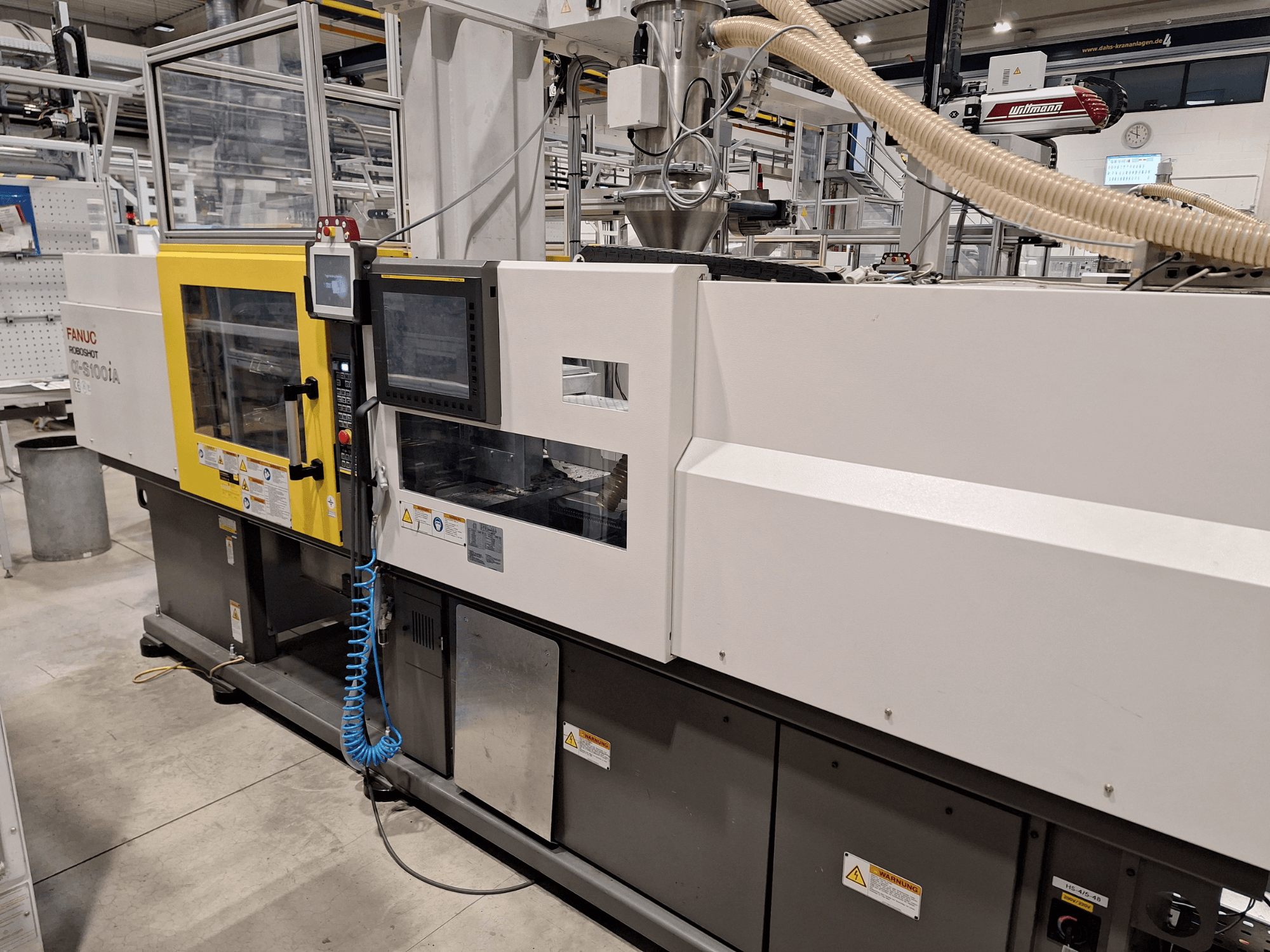 FANUC Roboshot α-S300iA įpurškimo liejimo mašinos priekinis vaizdas, kuriame matomas valdymo skydelis ir matomi pramoniniai komponentai.